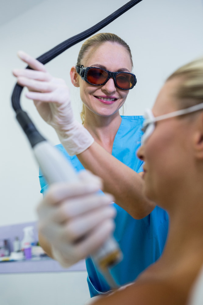 Dental professional performing teeth whitening on a patient, both wearing protective eyewear.