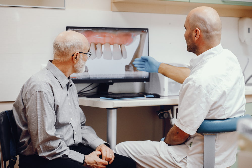 Dentist showing a patient tooth replacement options on a screen.