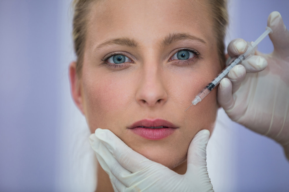 Woman receiving Botox treatment with a professional applying the injection to her face.