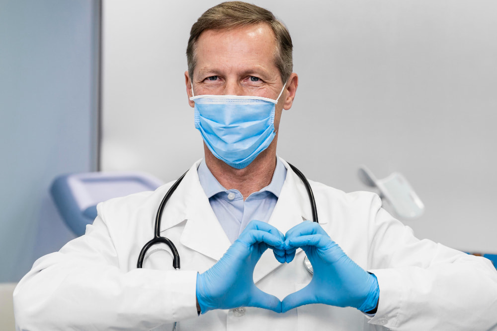 A dentist in a standing ovation, smiling and forming a heart shape with his hands.