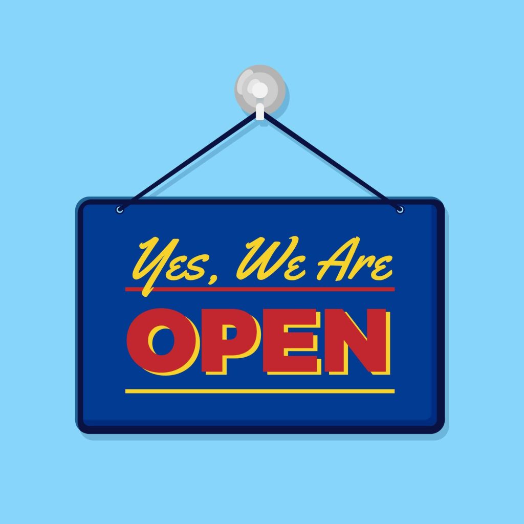 Hanging sign with "Yes, We Are OPEN" in bold red and yellow letters on a blue background,