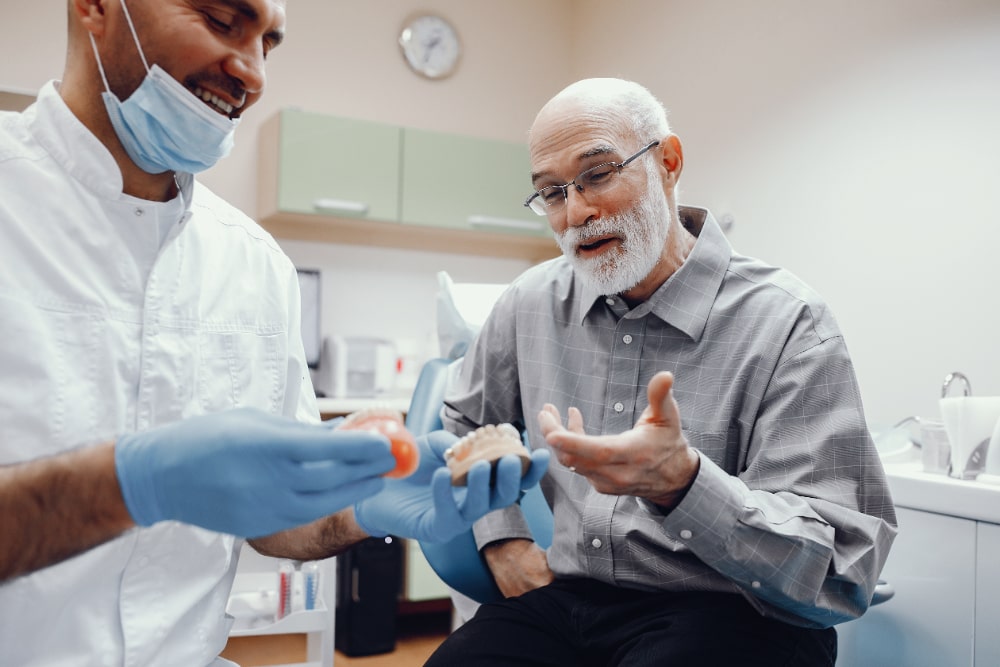 An elderly man sitting in a dental clinic, receiving oral health tips from a dentist