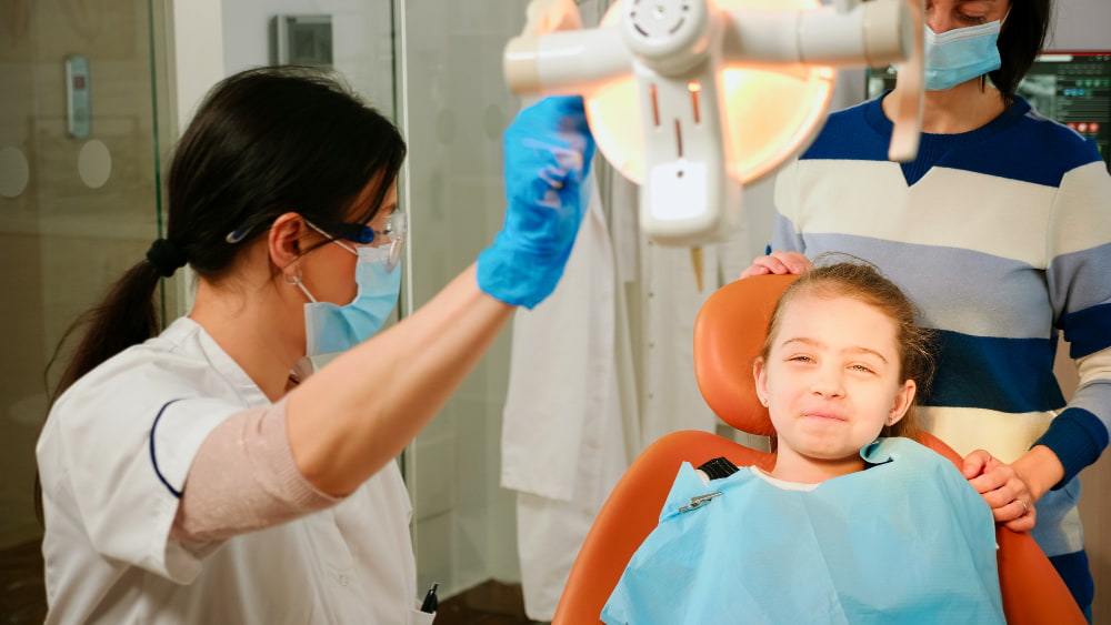 A child sitting in a dental clinic, receiving care for pediatric dentistry.