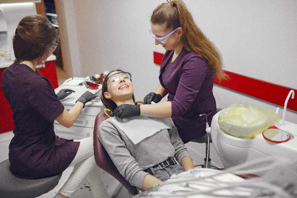 Two dentists in a clinic treating a woman undergoing root canal therapy