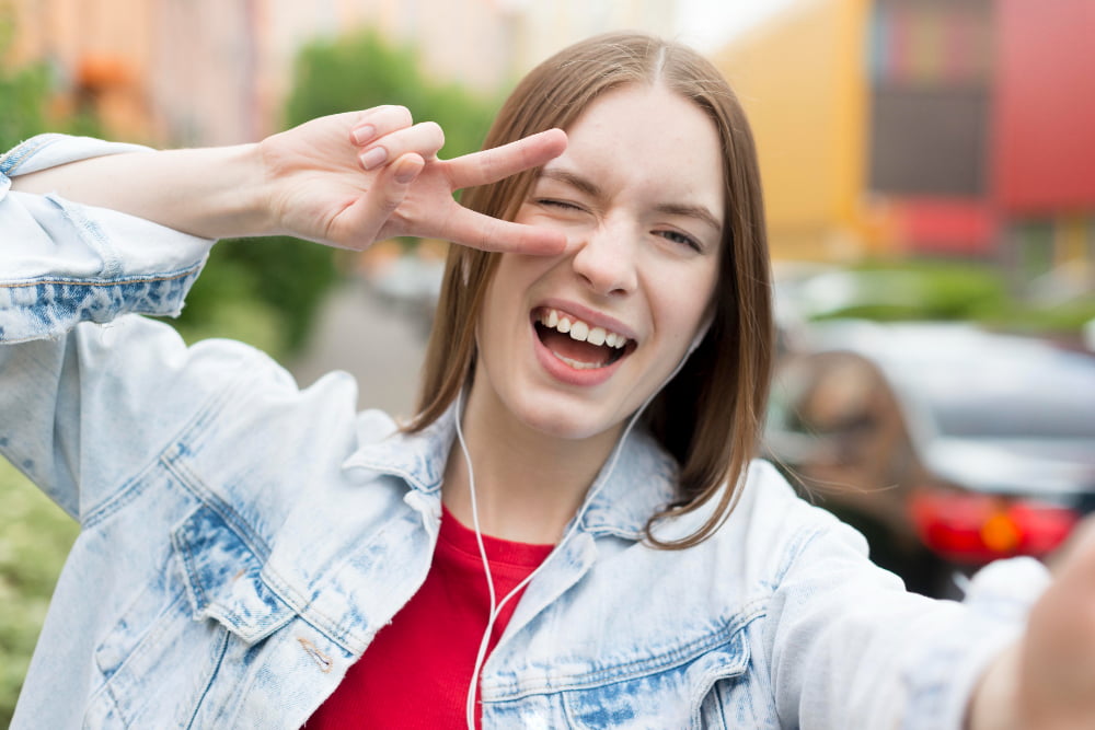 A young girl smiling with her hands raised, showing her teeth, and expressing excitement or joy.