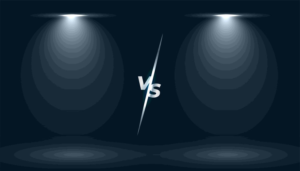 Dark stage with two spotlights cast circular light pools. A sharp "VS" is centered,