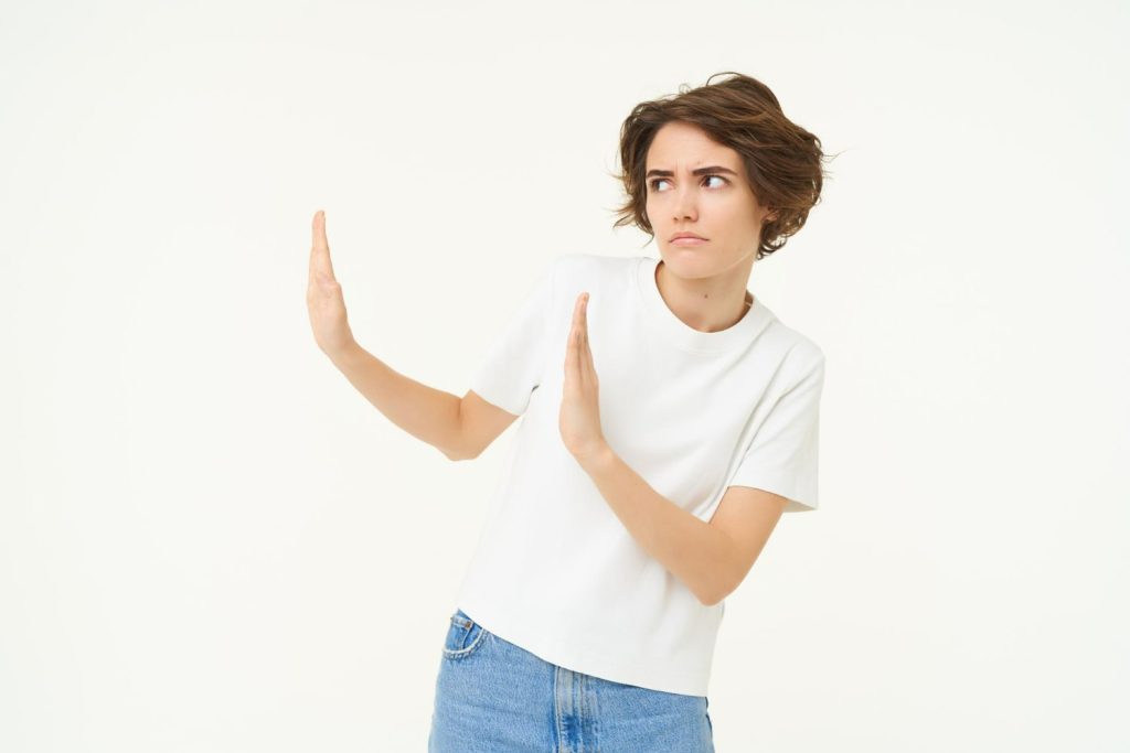 Woman in a white shirt and jeans gesturing disapproval, symbolizing what to avoid when cleaning your Invisalign case.