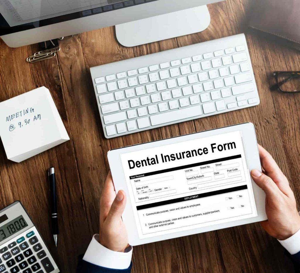 Person holding a tablet displaying a dental insurance form.